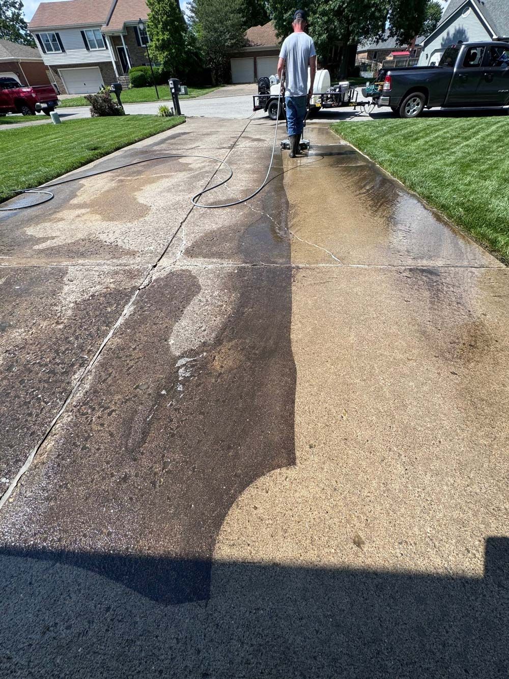 A man is cleaning a driveway with a pressure washer. - Bourbon City Softwash - Louisville, KY