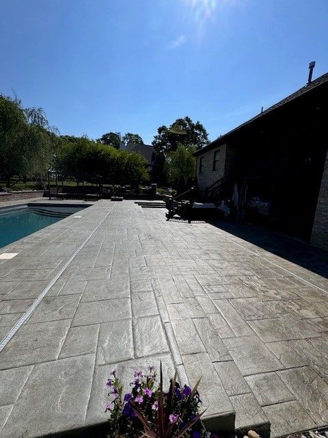 A patio with a swimming pool and a house in the background - Bourbon City Softwash - Louisville, KY