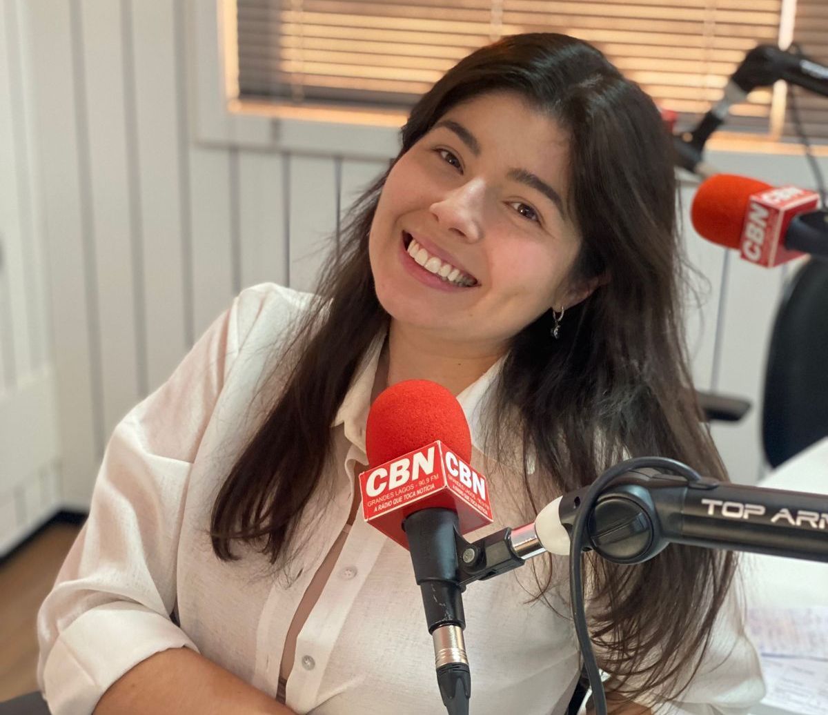 Uma mulher está sorrindo na frente de um microfone cbn
