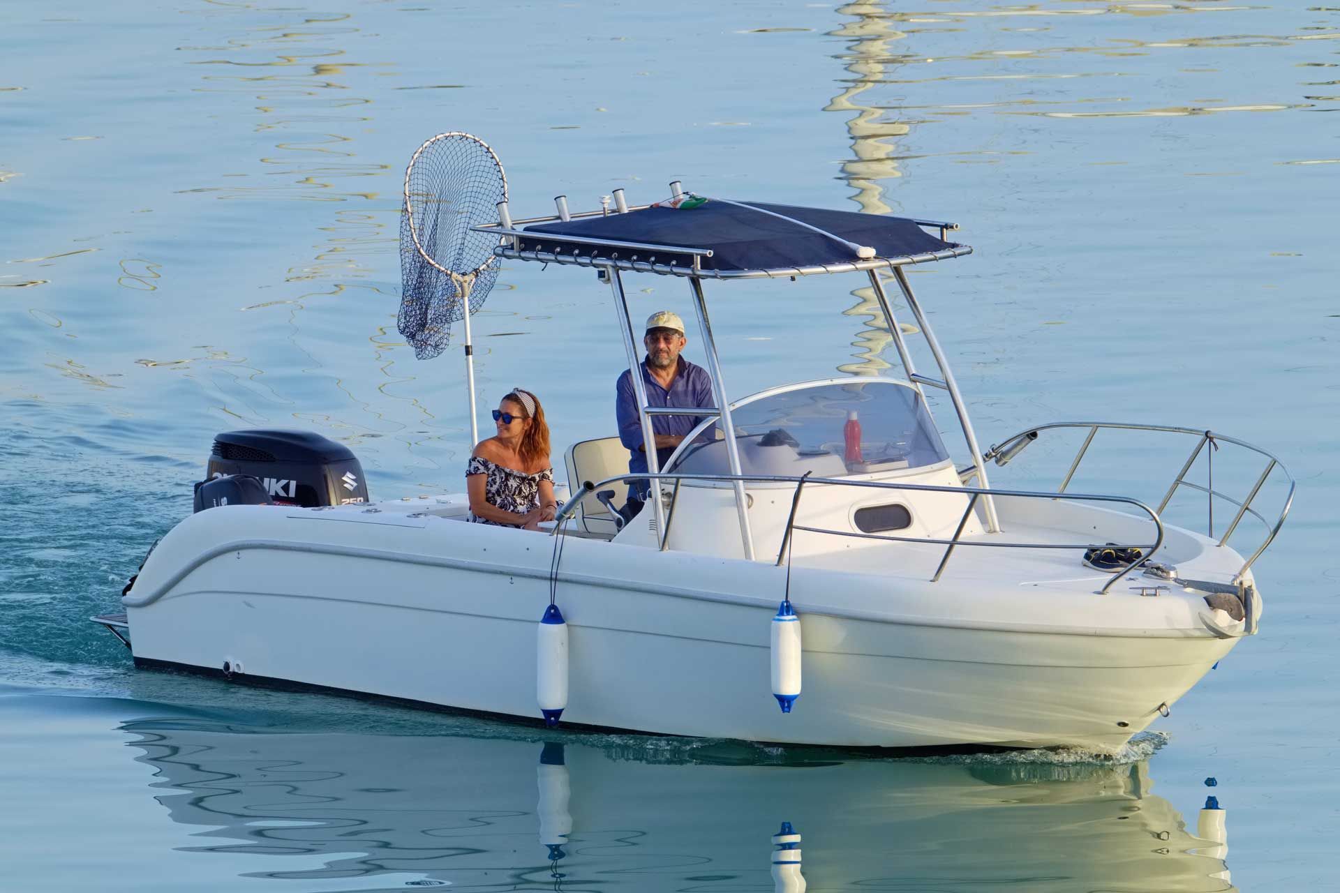 A man and a woman are sitting on a white boat in the water