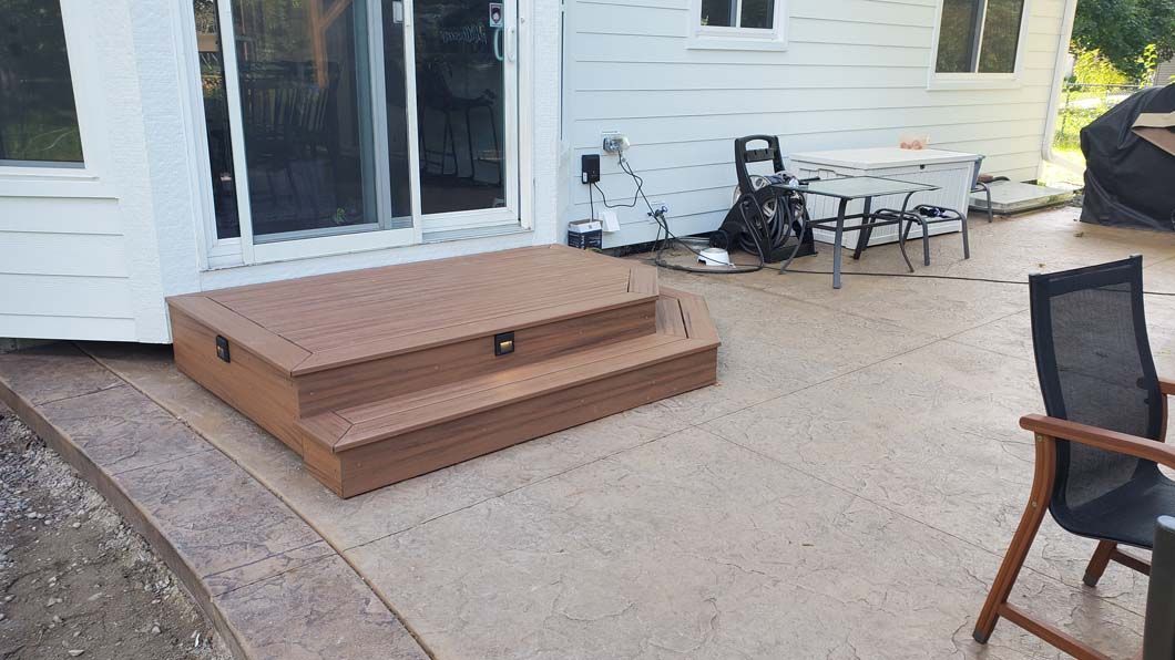A patio with stairs and chairs in front of a house.