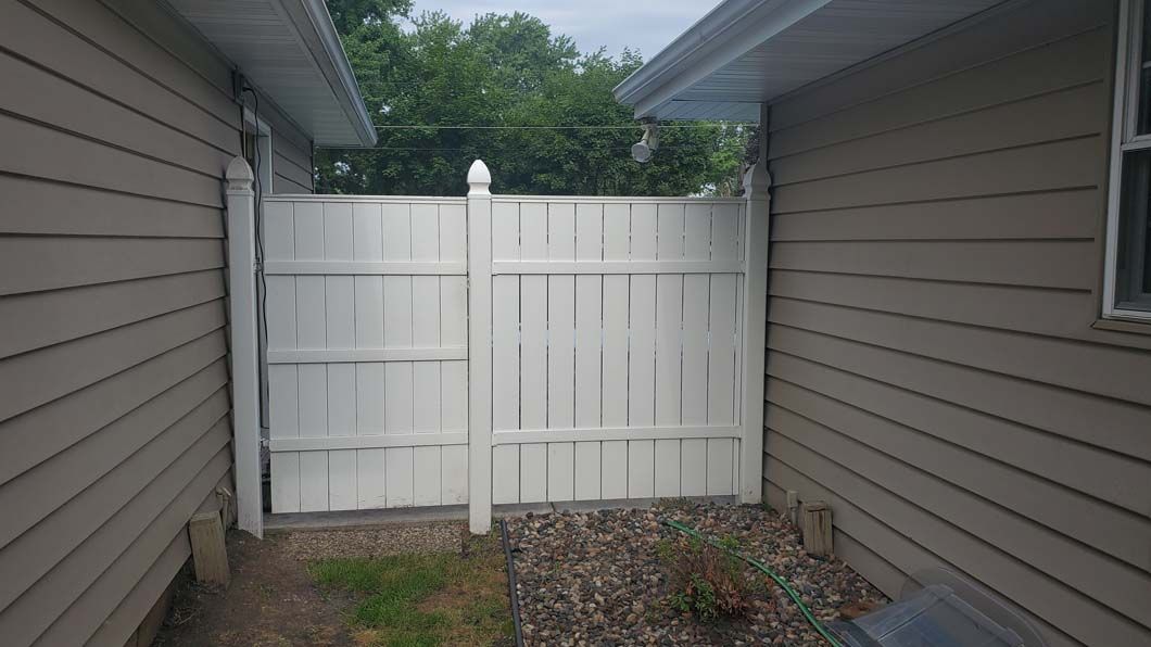 There is a white fence between two houses.