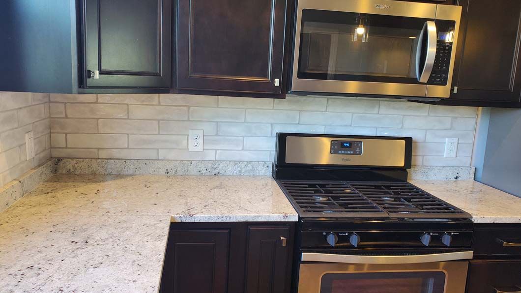 A kitchen with a stove , microwave , and granite counter tops.
