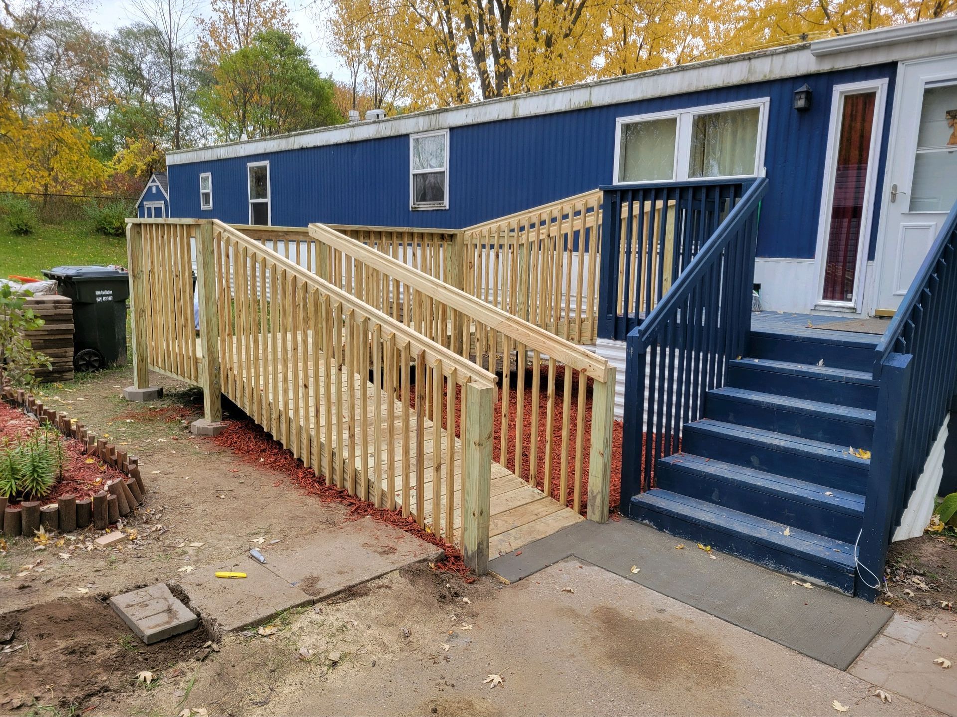 A mobile home with a wooden deck and stairs.
