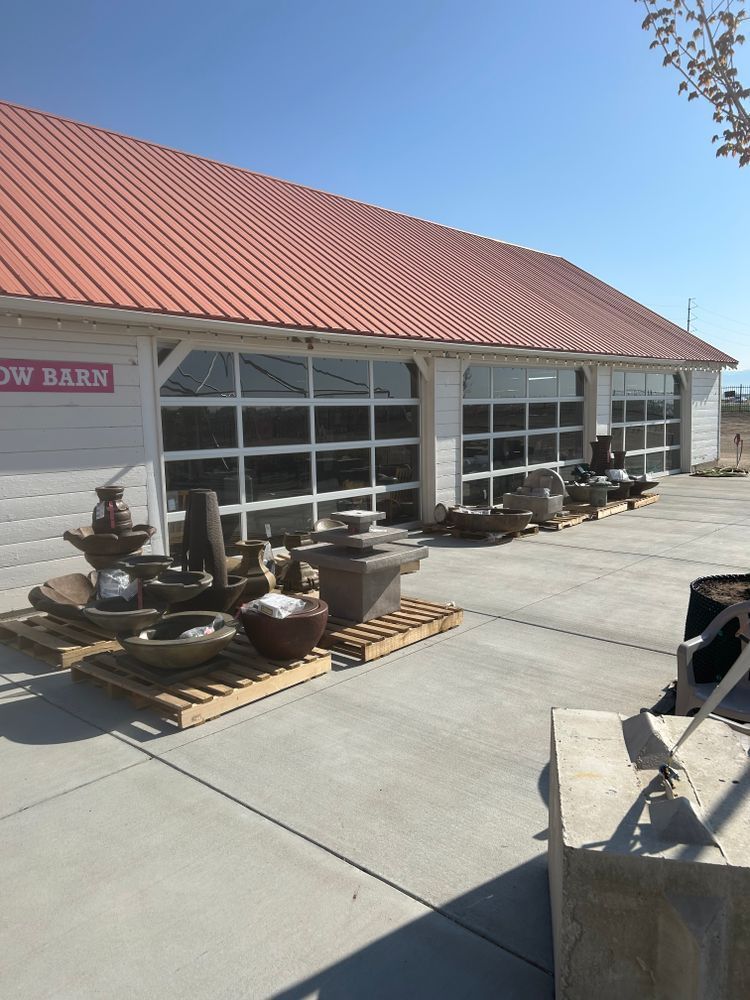 Outdoor display of pottery outside a white building with a red roof on a sunny day