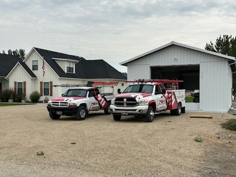 Two red-and-white emergency vehicles parked outside a white garage and house.