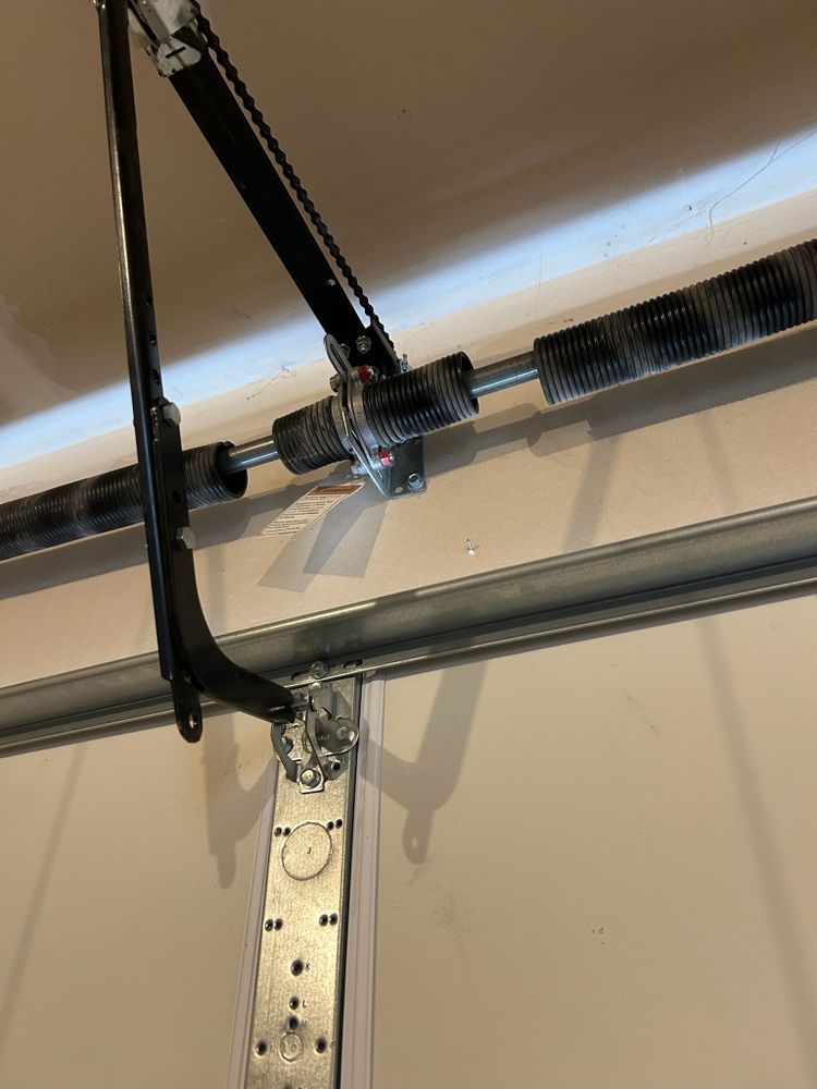 Garage door opener motor mounted to the ceiling with metal arm and rail system.