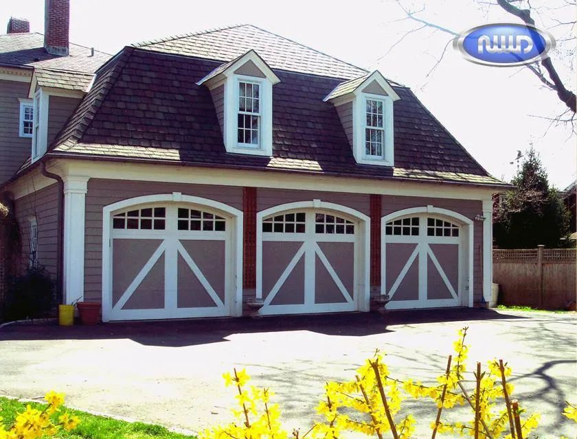 Red barn-style garage with three white doors and dormer windows on a sunny street.