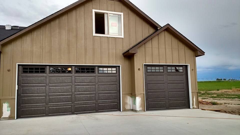 Brown garage with two dark brown doors and a small upper window on a concrete driveway.