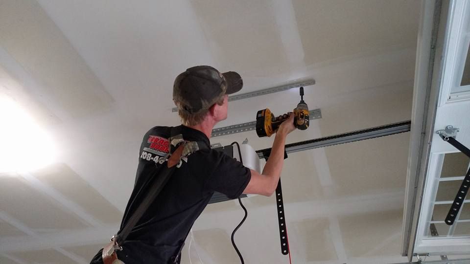 Worker using a tape measure on a garage door opener mounted to the ceiling
