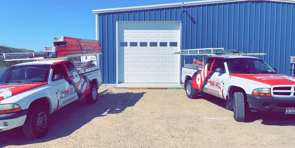 Empty two-car garage with white door, concrete floor, stainless fridge, and mop bucket.