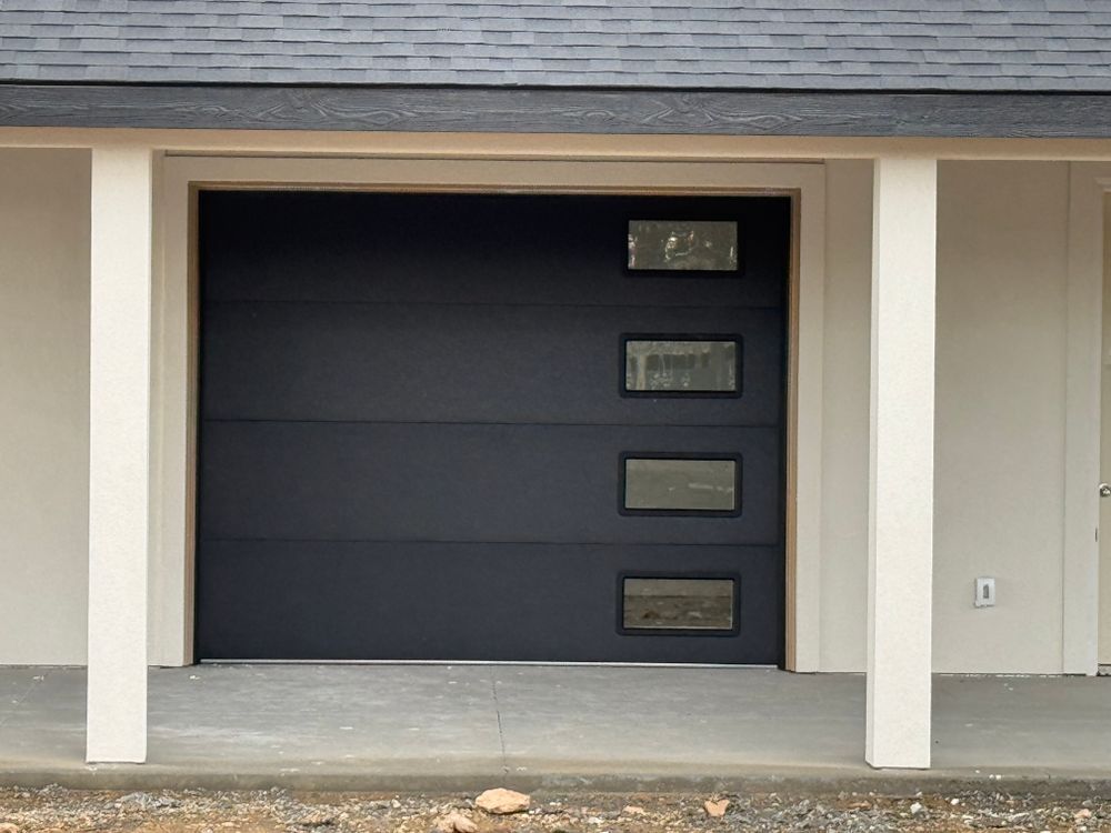 Modern garage door with four small windows under a covered driveway