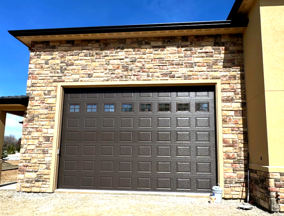 Brick house facade with a brown garage door under a blue sky