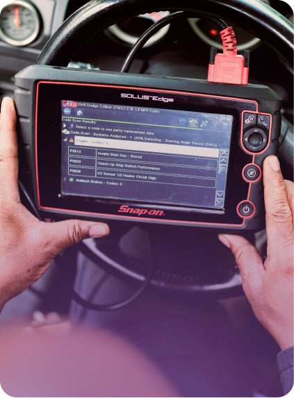 Hands holding an Autel scan tool showing car diagnostic data in a vehicle interior. | EZT Auto and Transmissions