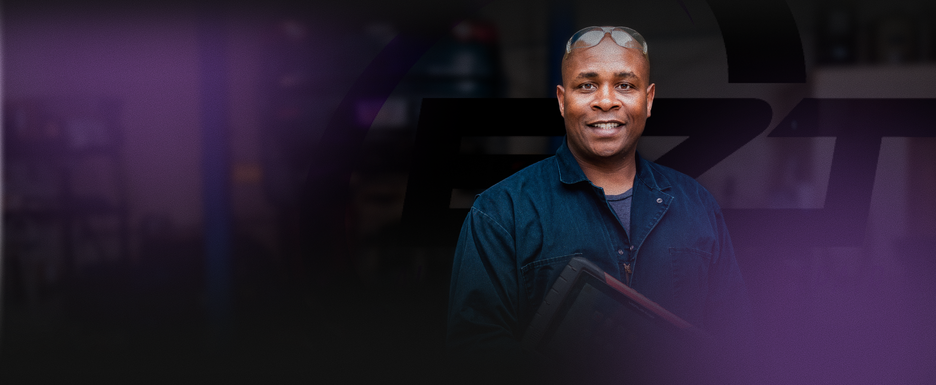 Portrait of a smiling man in a dark shirt against a purple-lit studio background | EZT Auto and Transmissions