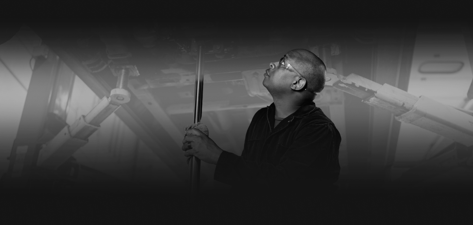 Person in glasses looking up at a microphone in a dim, black-and-white studio scene | EZT Auto and Transmissions