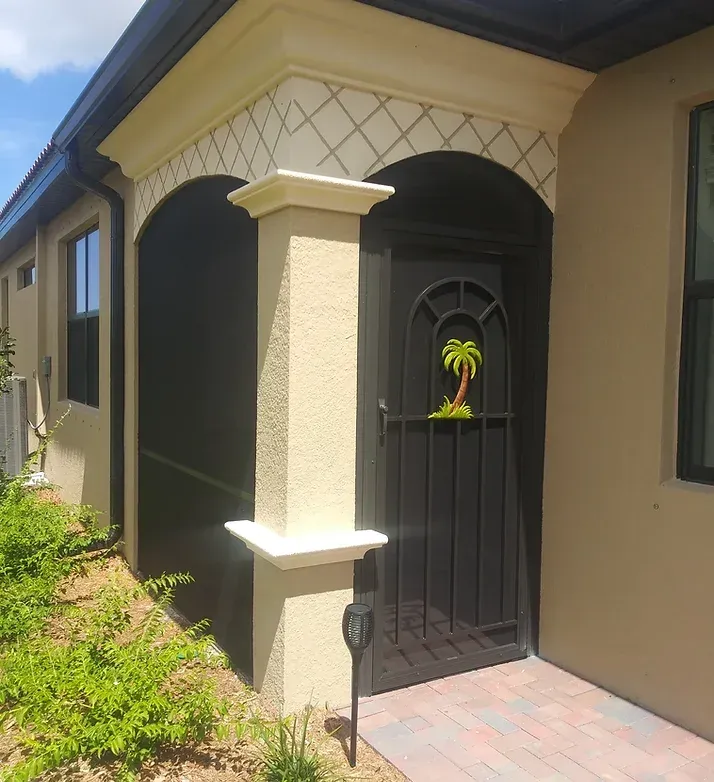 Exterior doorway with black metal gate, beige columns, and decorative archway.