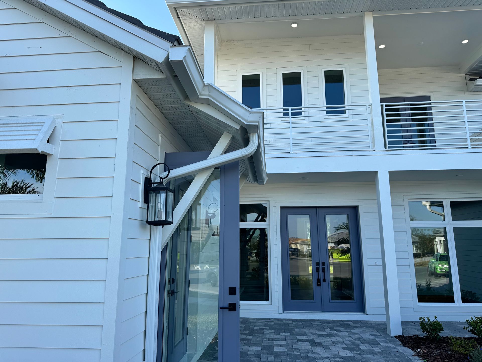 White house with gray trim, glass doors, and a second-story balcony.