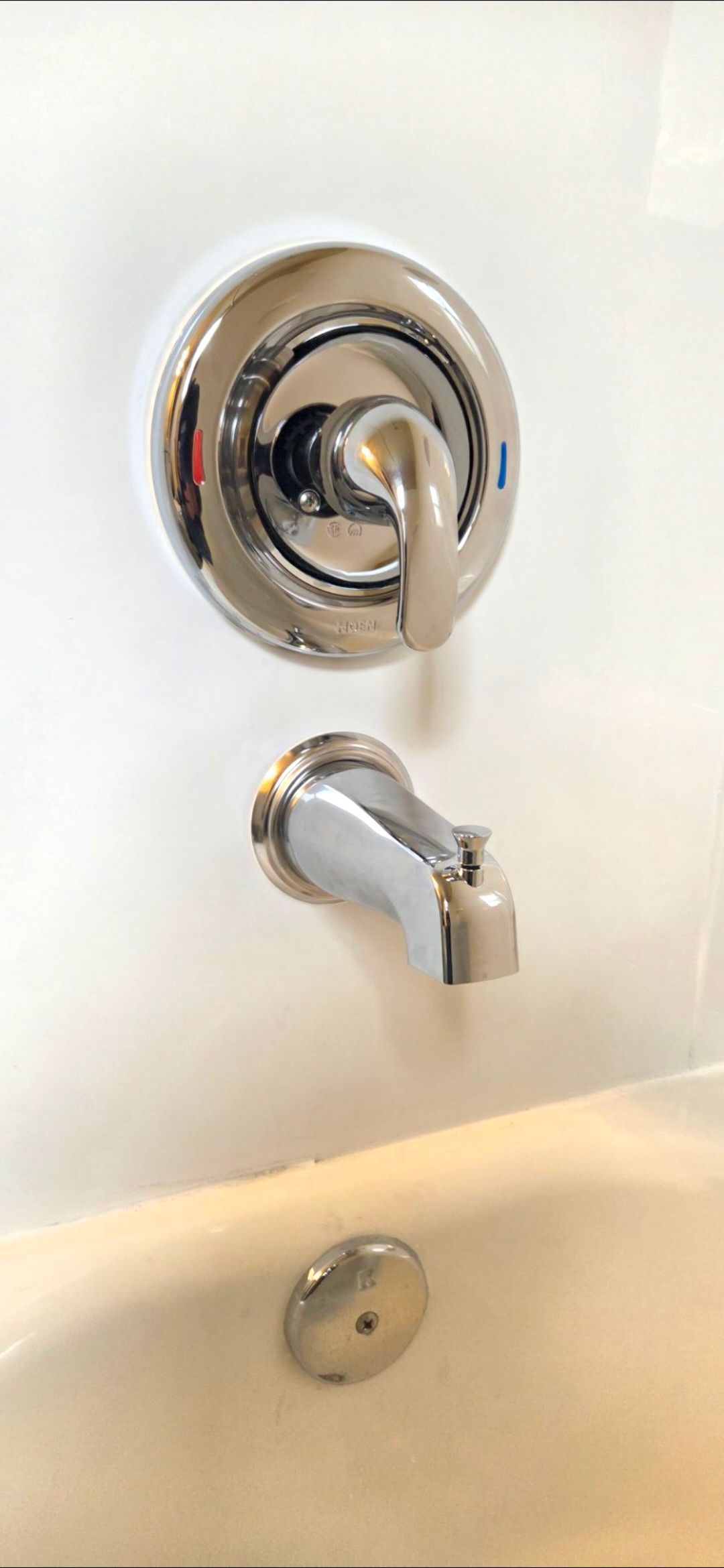 Chrome bathtub faucet and handle on a white tub wall.