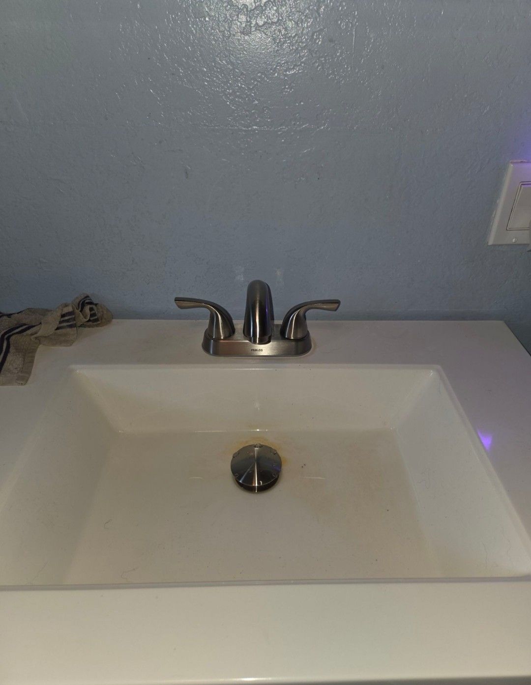 Bathroom sink with chrome faucet and a white countertop against a gray wall