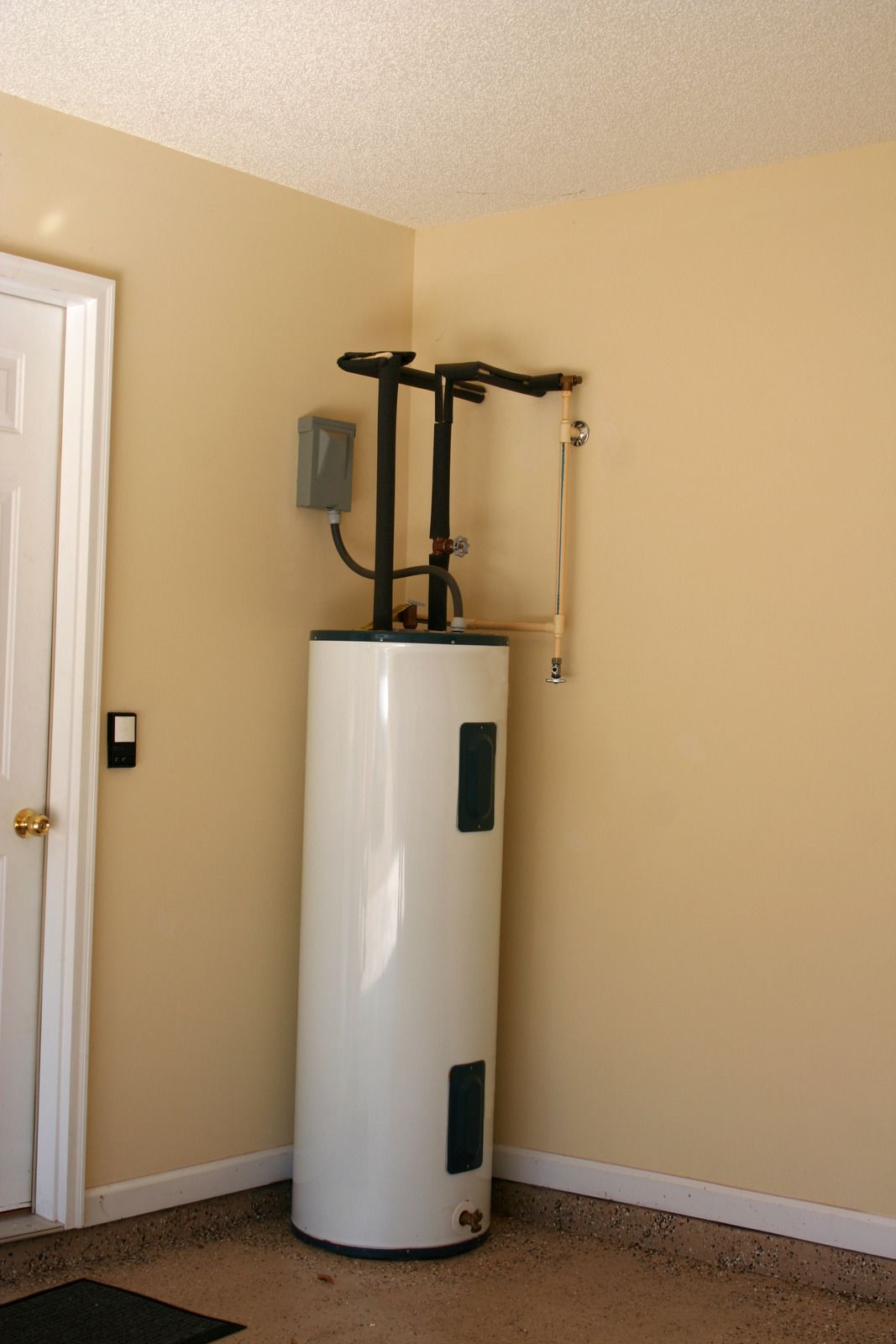 White water heater with black metal rack in a beige corner room with a white door and carpeted floor