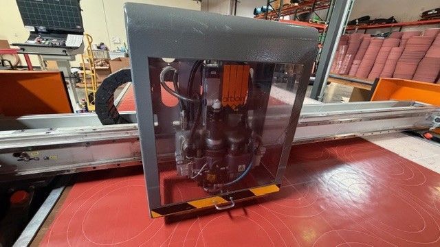 Atom Flash Cutter with a clear front cover on a red workbench in an industrial workshop