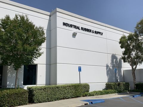 Industrial Rubber & Supply building exterior with white facade and trees in front