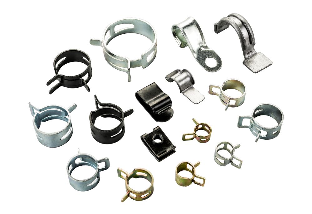 Assorted metal hose clamps and pipe clips arranged on a white background