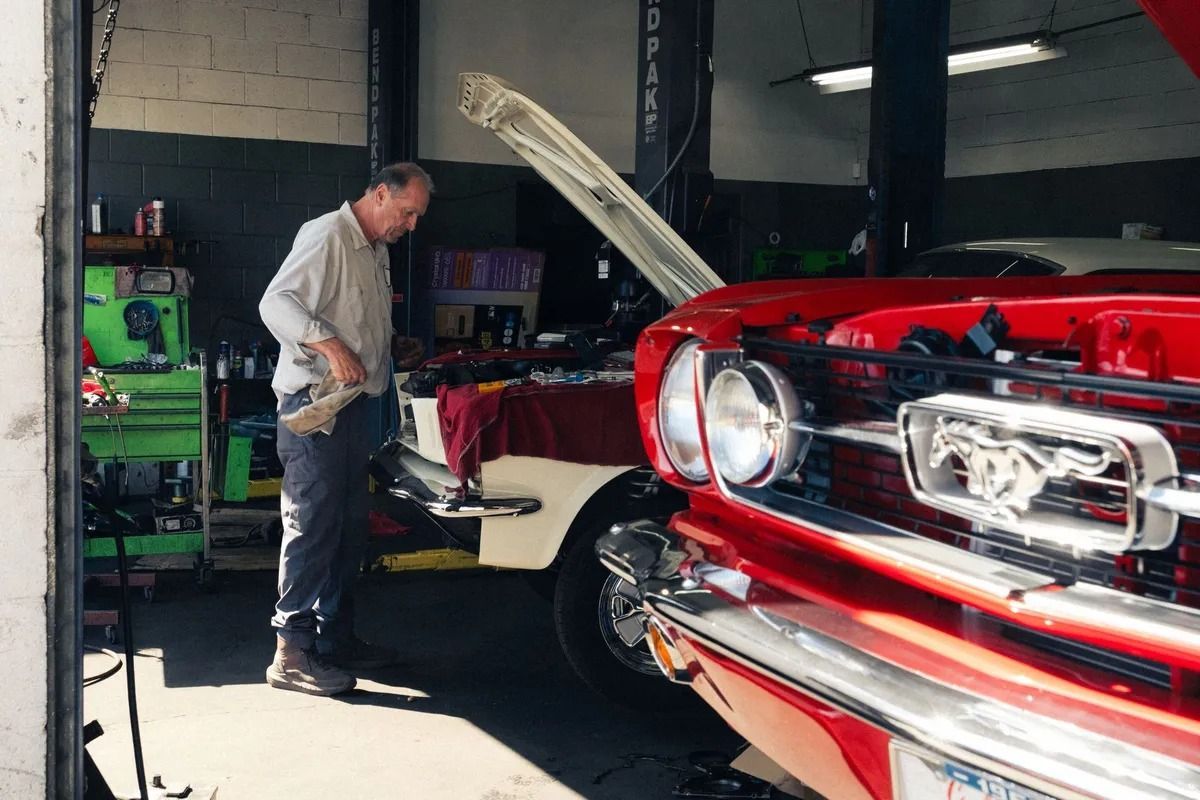 Mechanic working on a red classic car in a garage with the hood open | Bob's Auto Repair