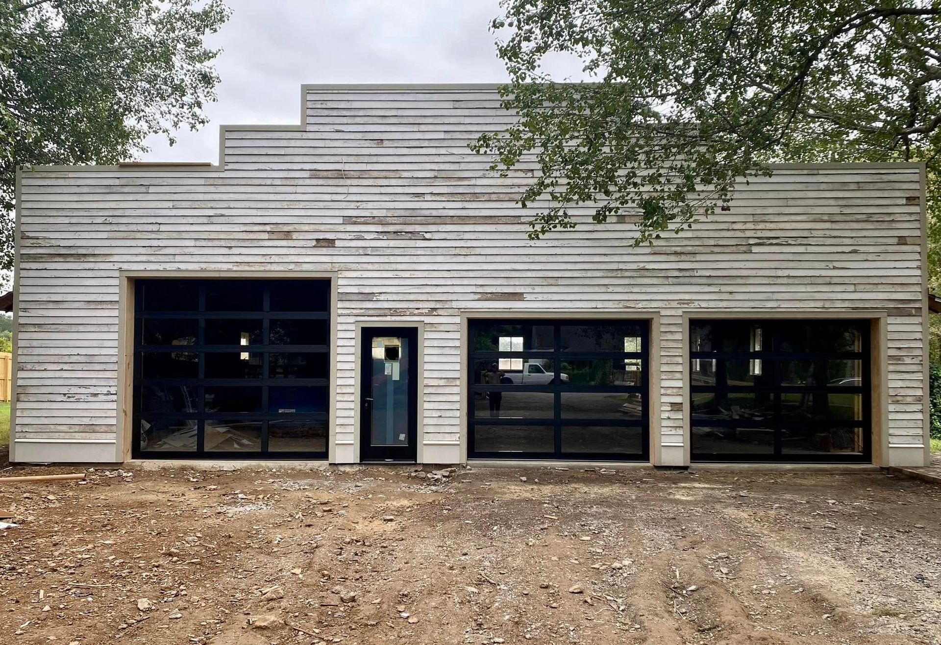 Front view of a small weathered white storefront with dark windows and a central door, surrounded by dirt. Front view of a small weathered white storefront with dark windows and a central door, surrounded by dirt.
