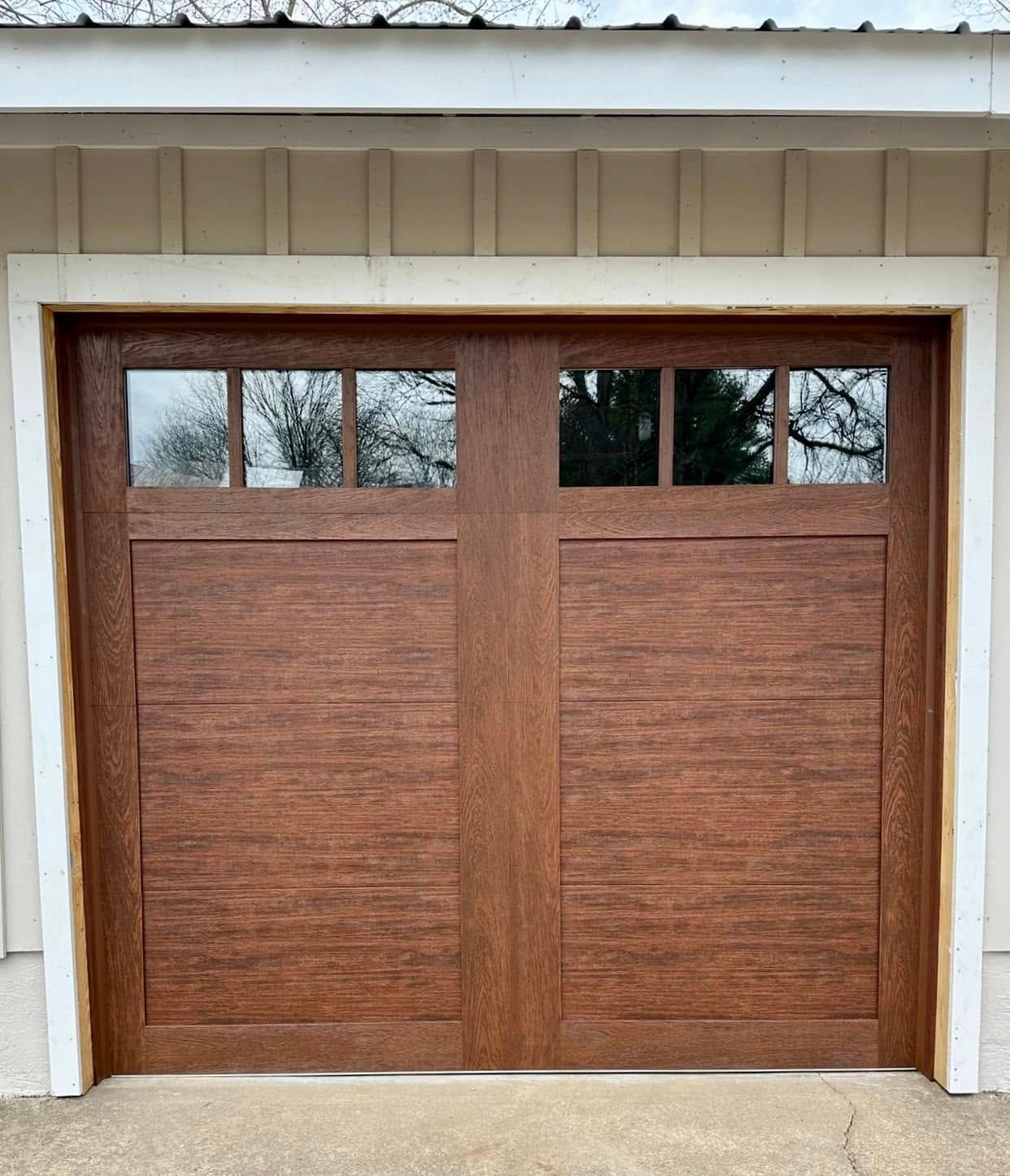Wooden double garage door with small windows in a beige house exterior Wooden double garage door with small windows in a beige house exterior