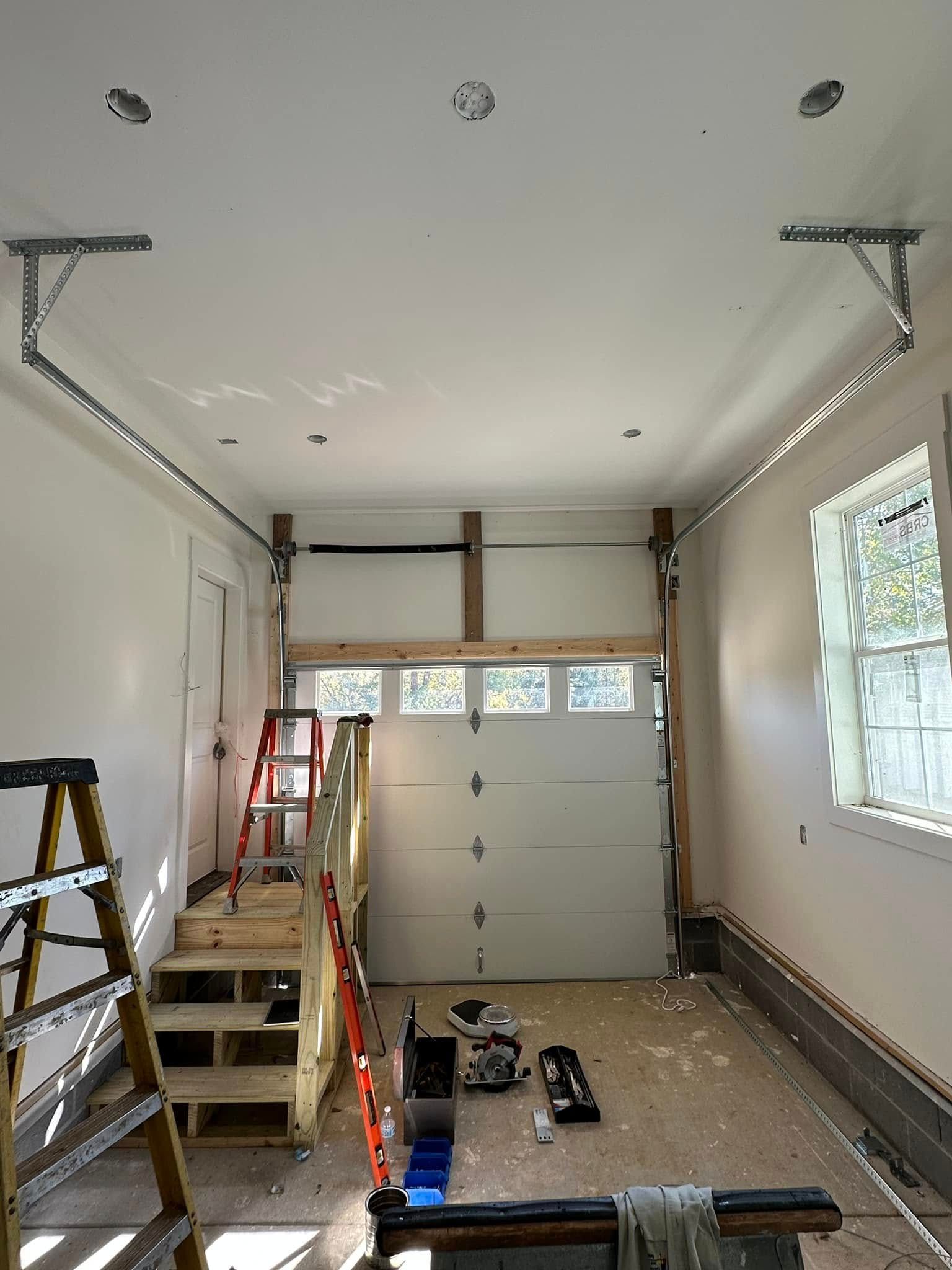 Garage under renovation with ladders, tools, and unfinished drywall on the walls and ceiling Garage under renovation with ladders, tools, and unfinished drywall on the walls and ceiling