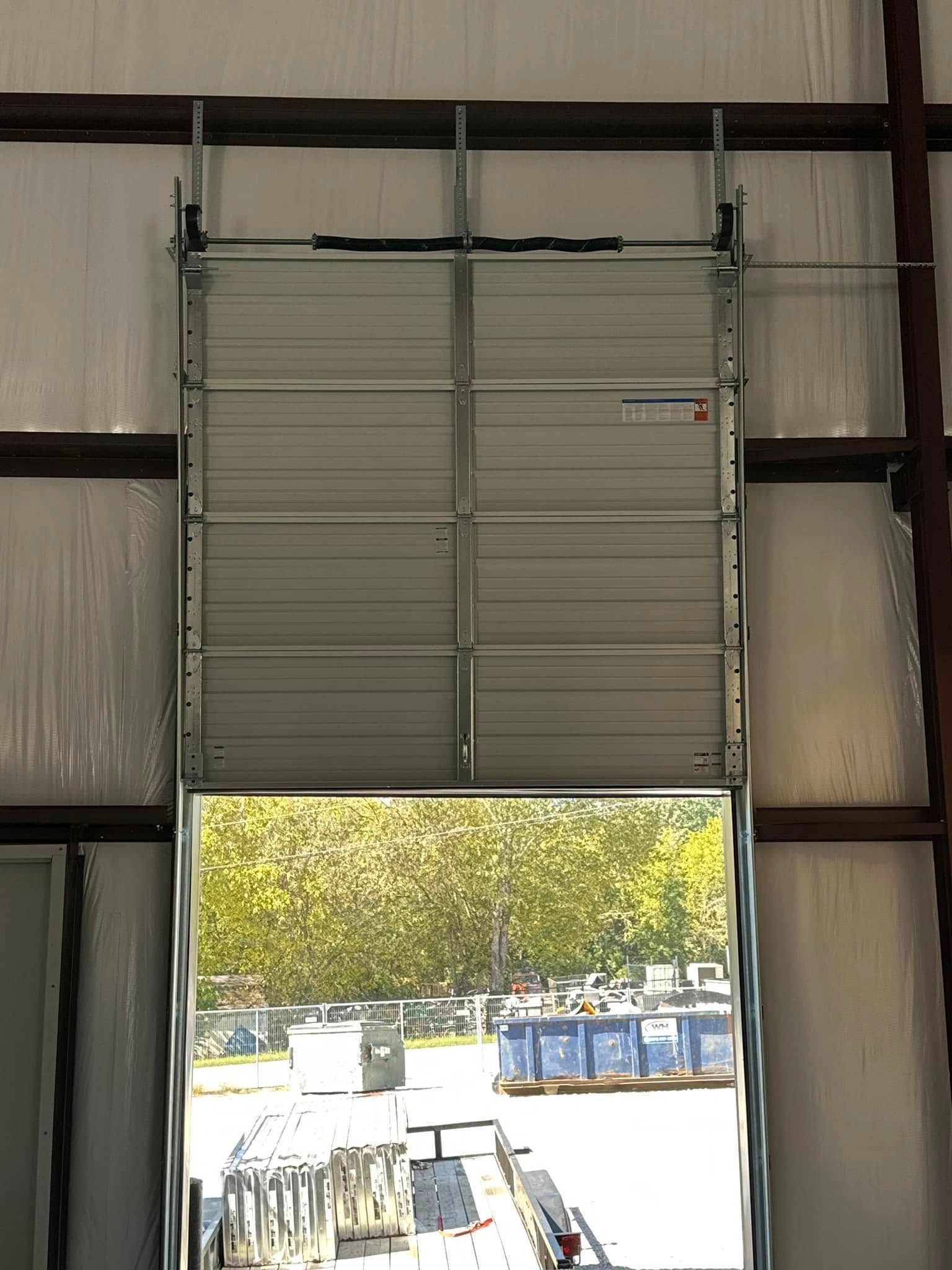 Partially open roll-up garage door with sunlight showing an outdoor lot Partially open roll-up garage door with sunlight showing an outdoor lot