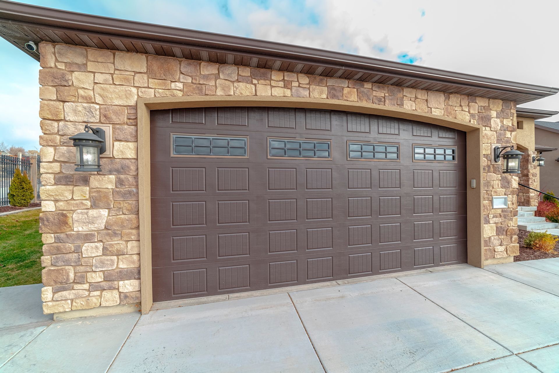Stone house garage with a dark brown double door and wall-mounted lanterns Stone house garage with a dark brown double door and wall-mounted lanterns