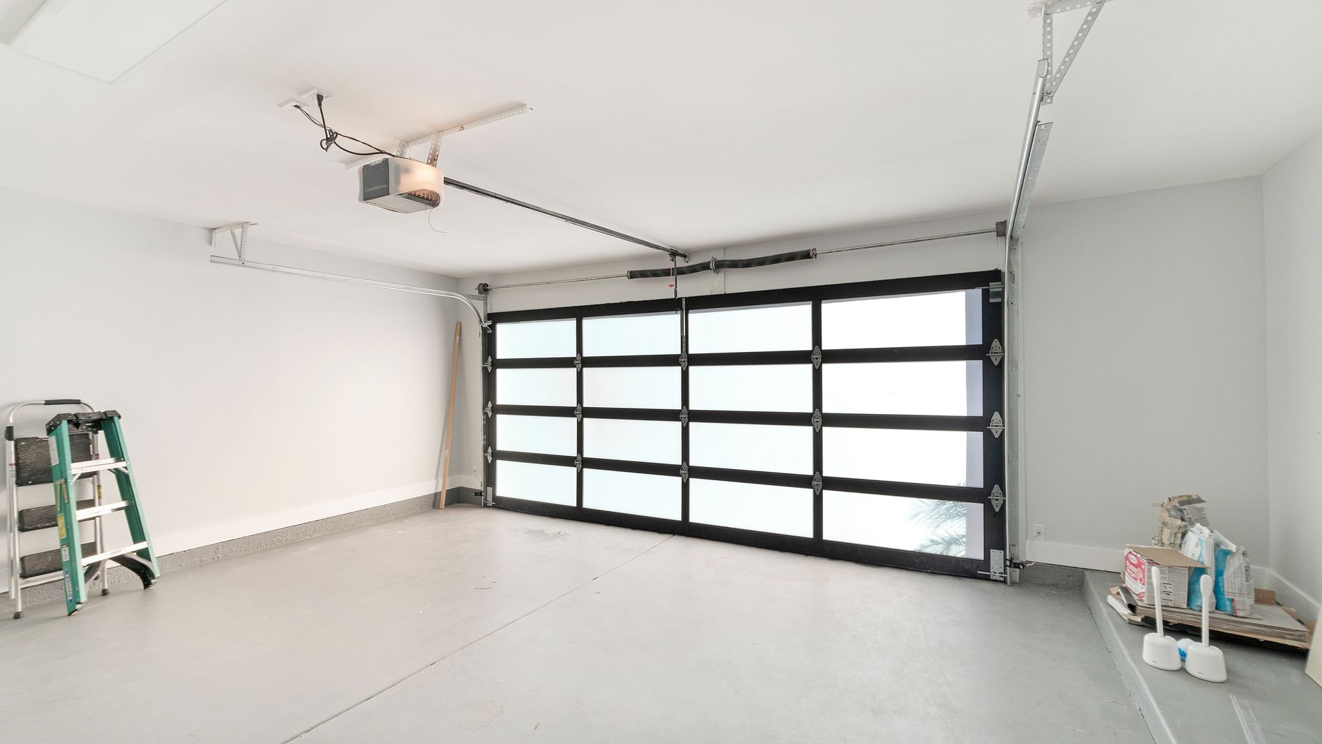 Bright empty garage with a large frosted glass door, white walls, and a ladder on the left. Bright empty garage with a large frosted glass door, white walls, and a ladder on the left.