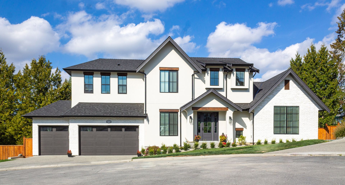 Two-car garage in a brick townhouse with black doors and a side entrance under windows.