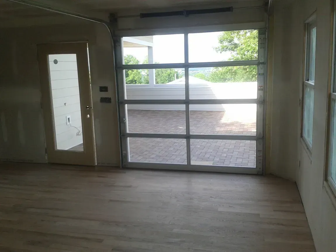 Empty room with wood floor, front glass doors, and a side door with frosted glass panels.