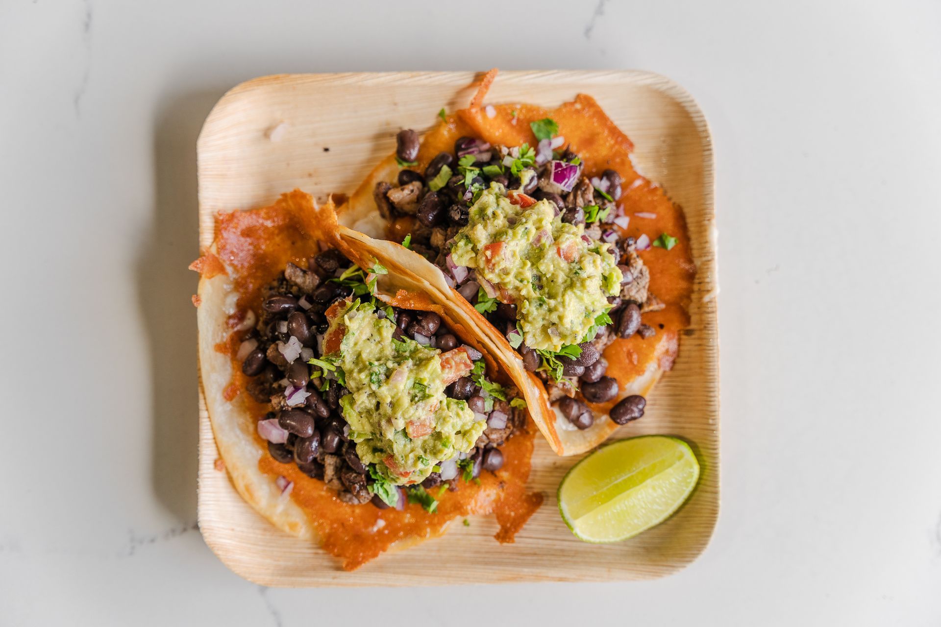 Carne asada street tacos perron with beans, guacamole, red onions and crispy cheese by chubasco tacos.