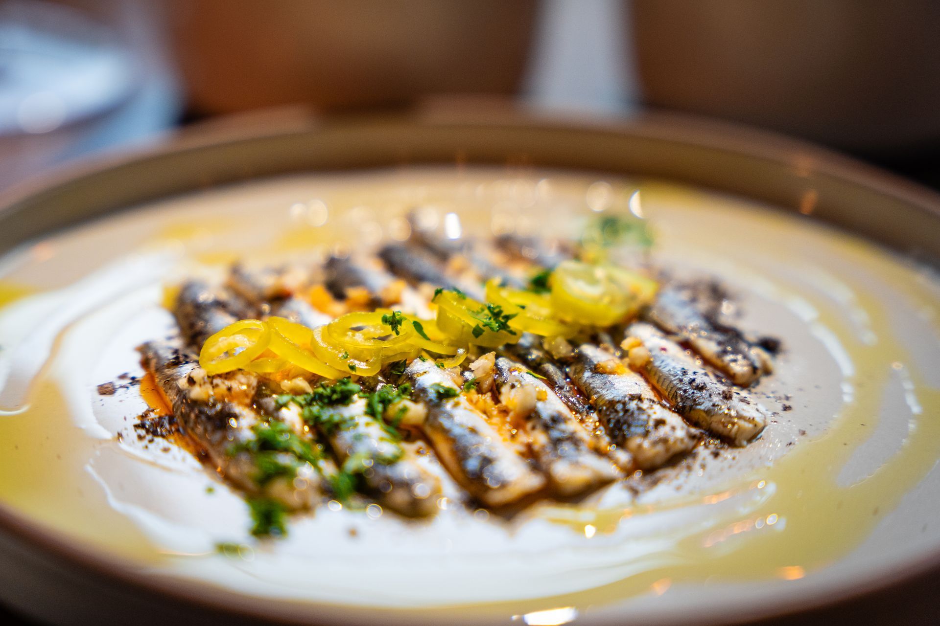 Plated grilled fish over creamy sauce, garnished with herbs and lemon slices