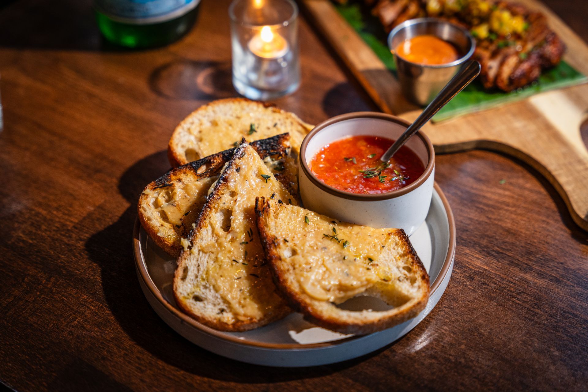 Garlic bread slices on a plate with marinara dipping sauce on a rustic wooden table