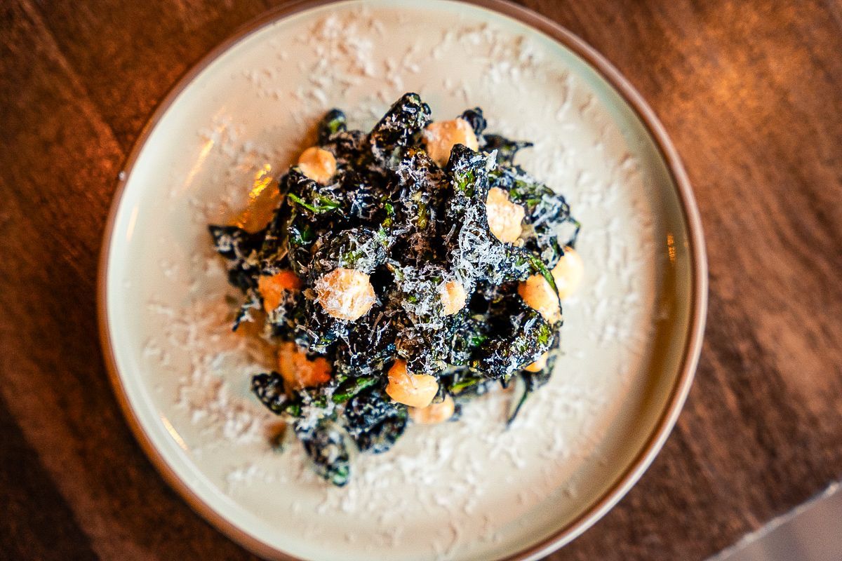 Bowl of creamy soup topped with black beans, corn, herbs, and crumbled cheese on a wooden table