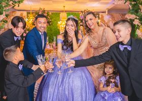 Group toasting at a formal celebration, with a woman in a purple gown centered among guests in suits.