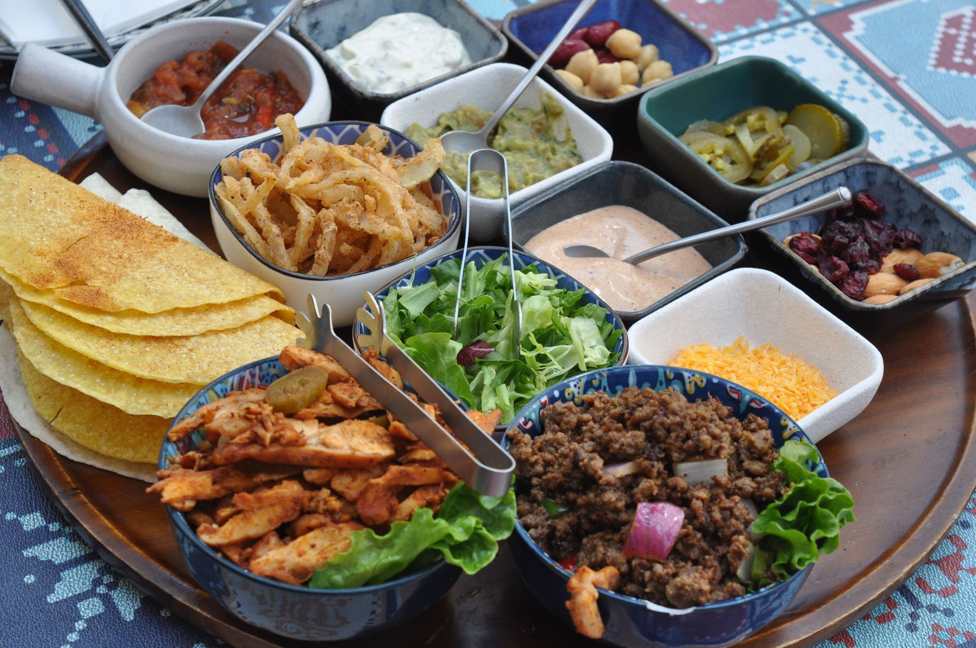 Mexican meal spread with tacos, grilled chicken, rice, guacamole, chips, and dips on a table