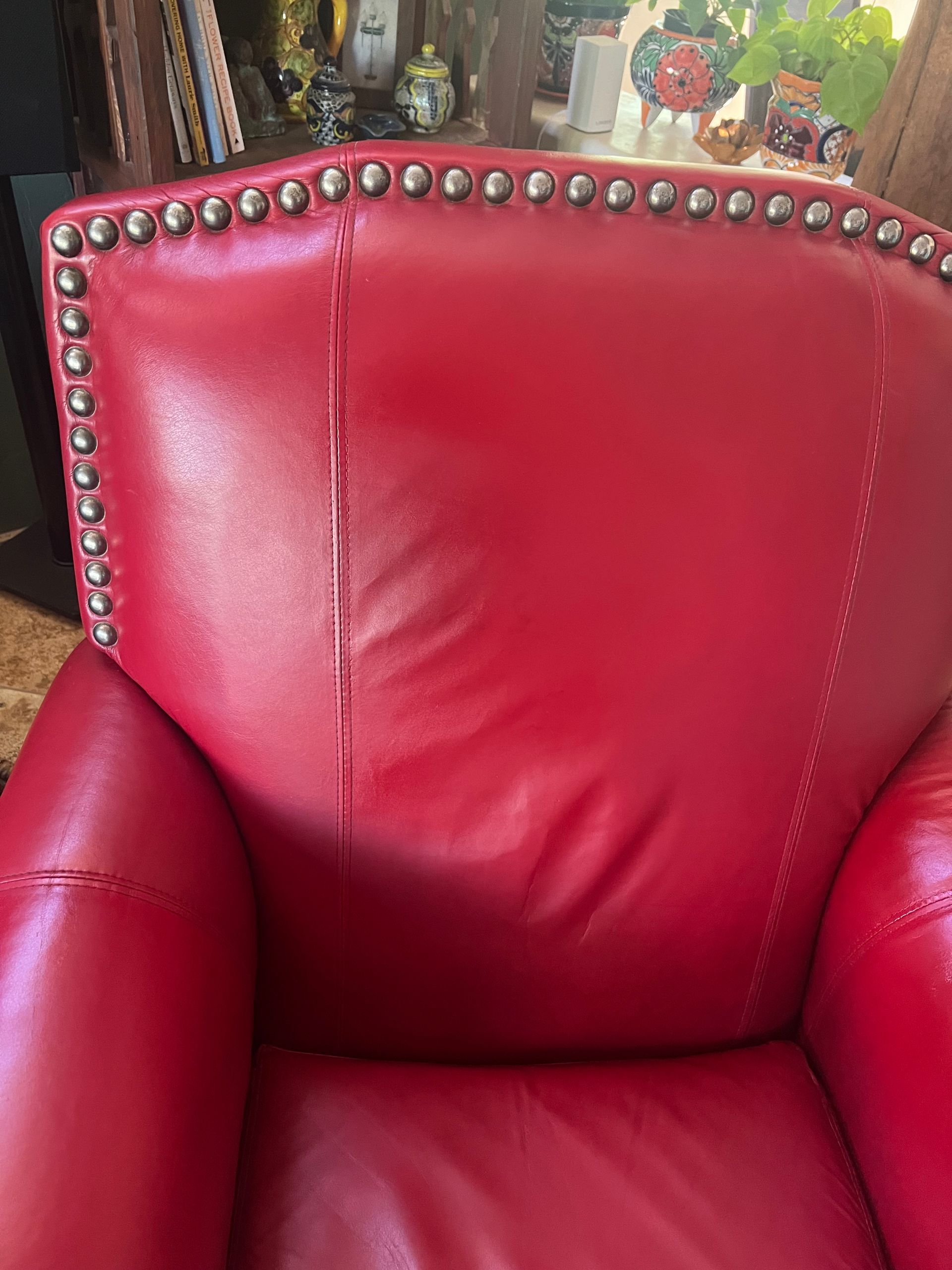Red leather armchair with nailhead trim in a cozy indoor setting