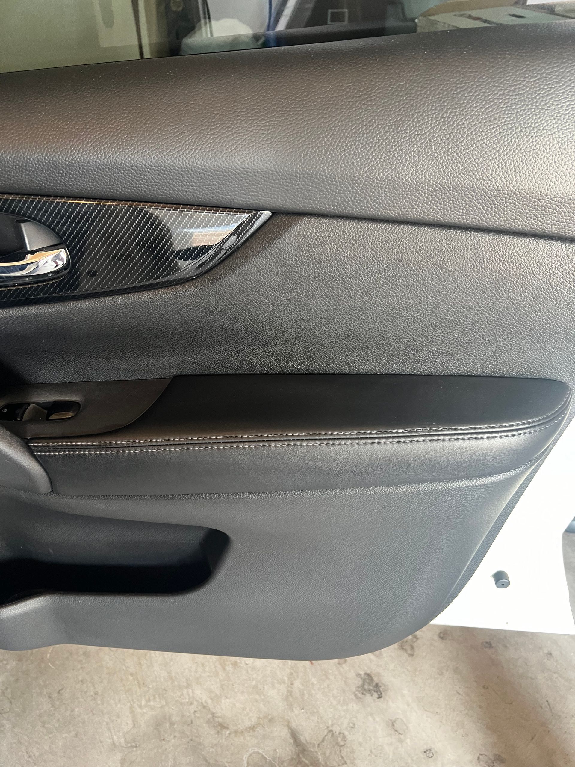 Close-up of a gray car door interior with black handle and storage pocket
