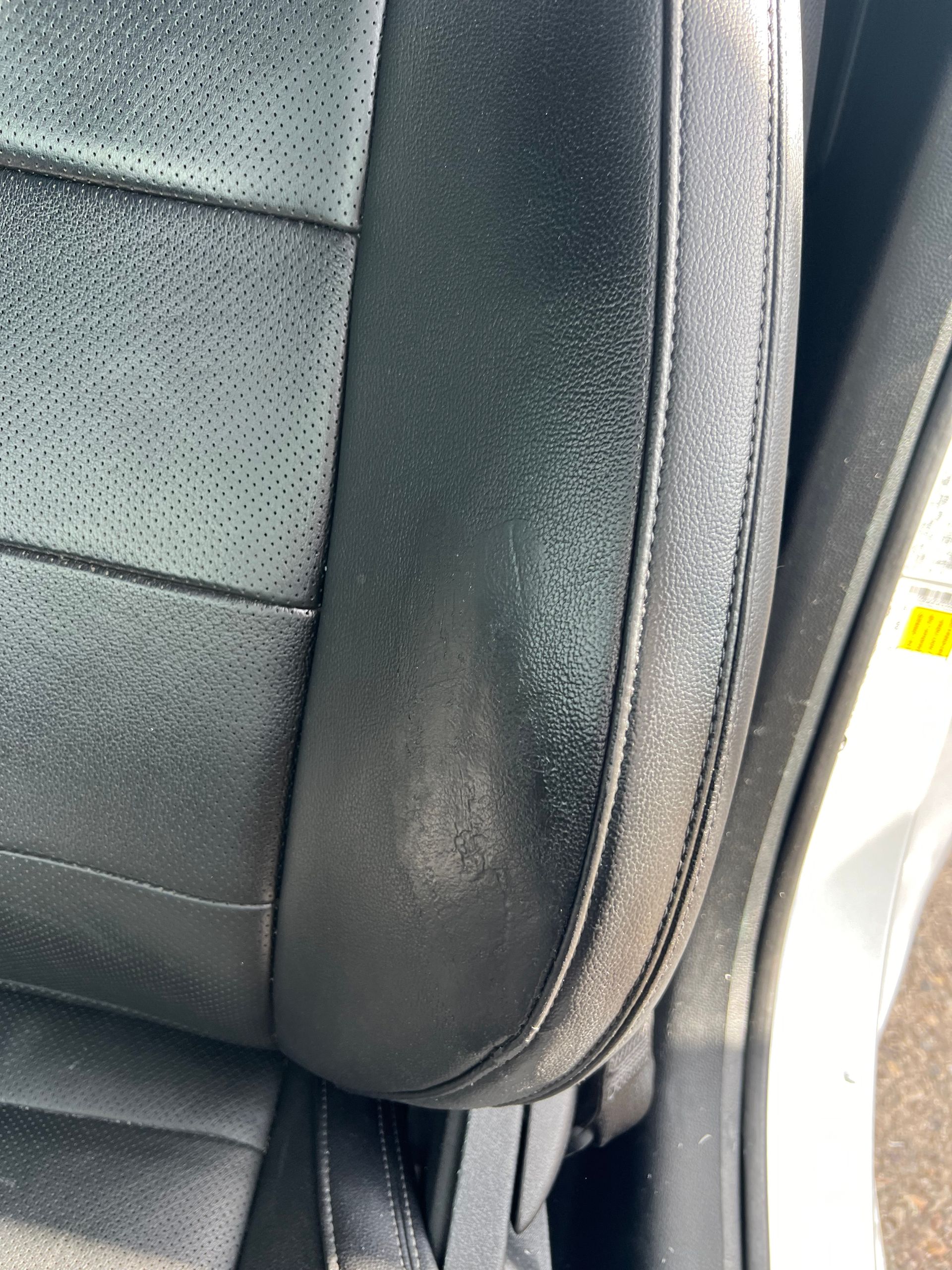 Close-up of a black car seat with visible wear and fading on the side bolster