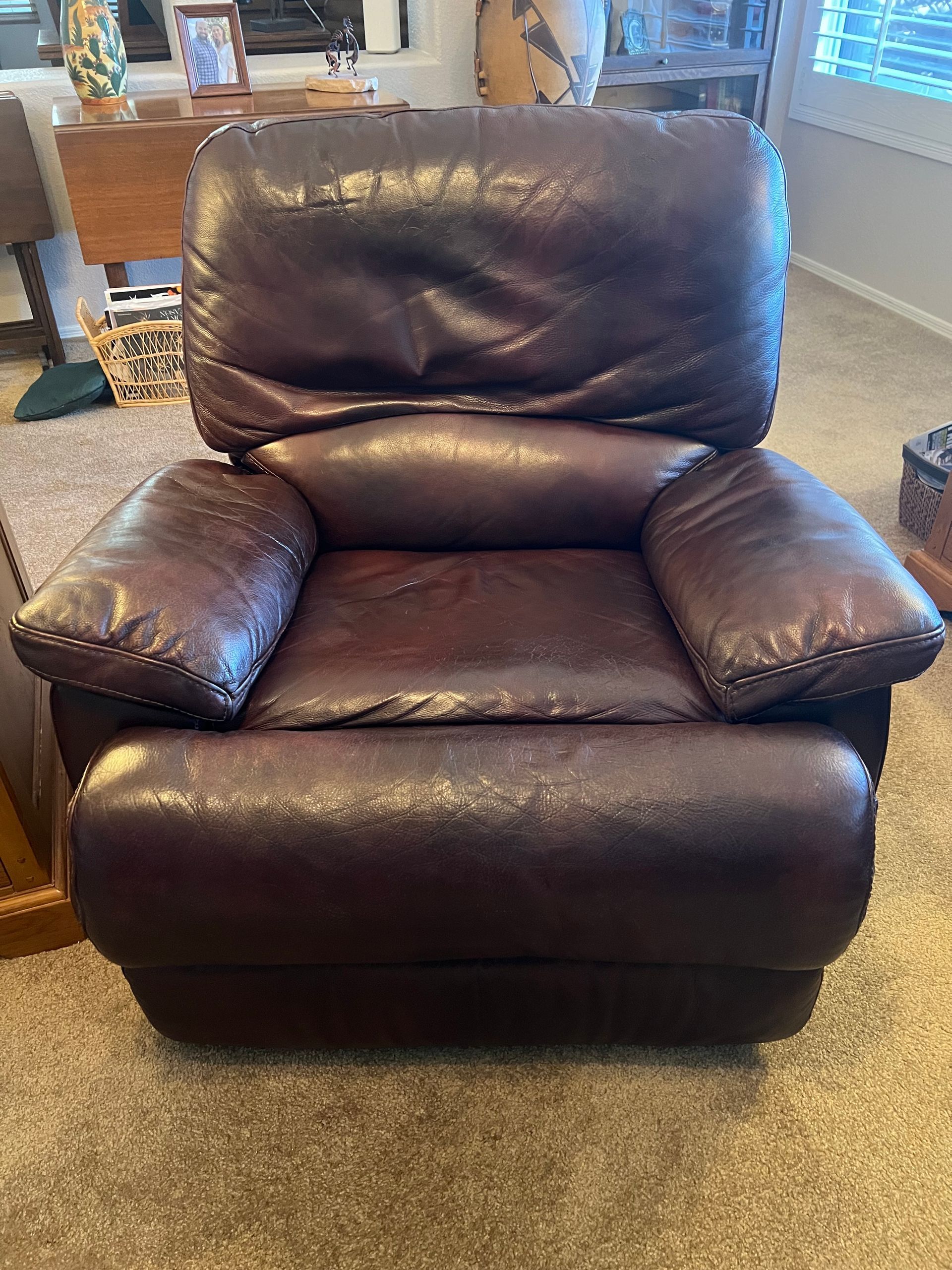 Brown leather recliner chair in a carpeted living room.