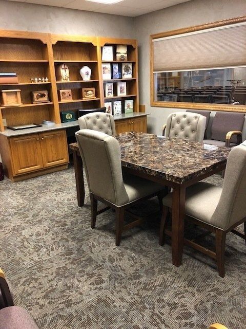 Office conference room with wooden shelves, marble table, cushioned chairs, and a window overlooking another room