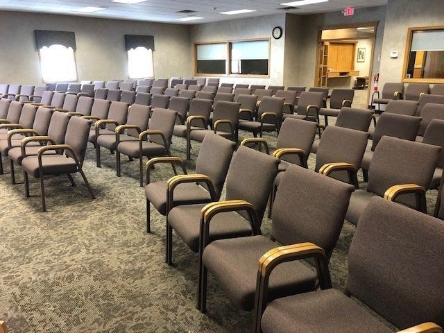 Empty conference room with rows of brown chairs and carpeted floor under soft indoor lighting