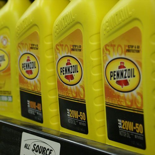 Several bottles of pennzoil are lined up on a shelf